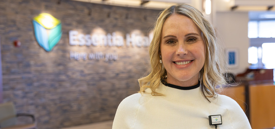 Woman with blonde hair smiling inside of a hospital lobby.
